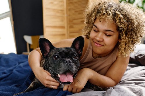 young-woman-cuddling-with-french-bulldog-on-her-bed